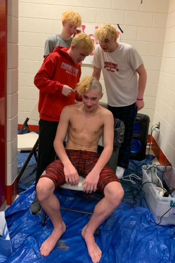 The Boys Varsity Swim Team shaves their teammates head.