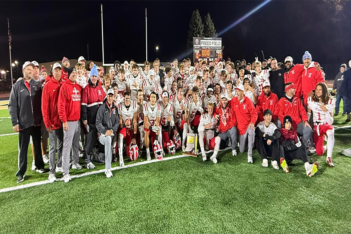 The varsity football team and coaches pose with their plaque they won from their sectional championship game.