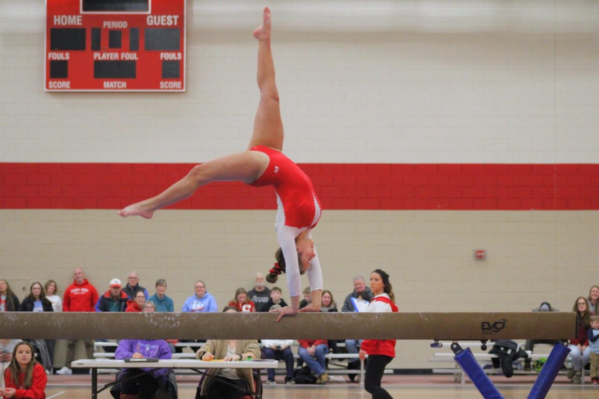 Mia Muvceski (10) conducts a back walkover on the balance beam.