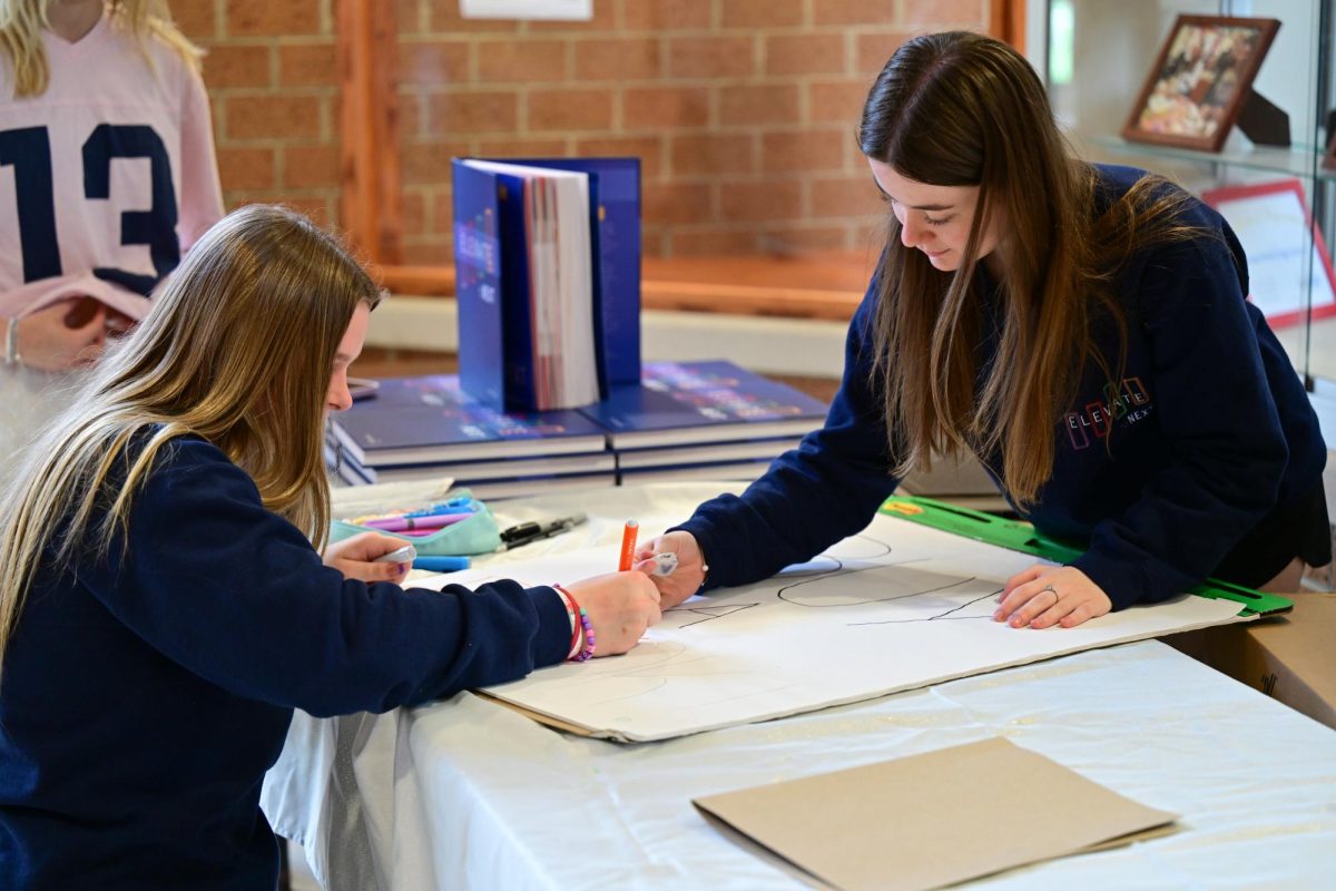 Adyson Graegin (10) and Brooklyn Gargano (10) color another poster to be put up for yearbook distribution. 