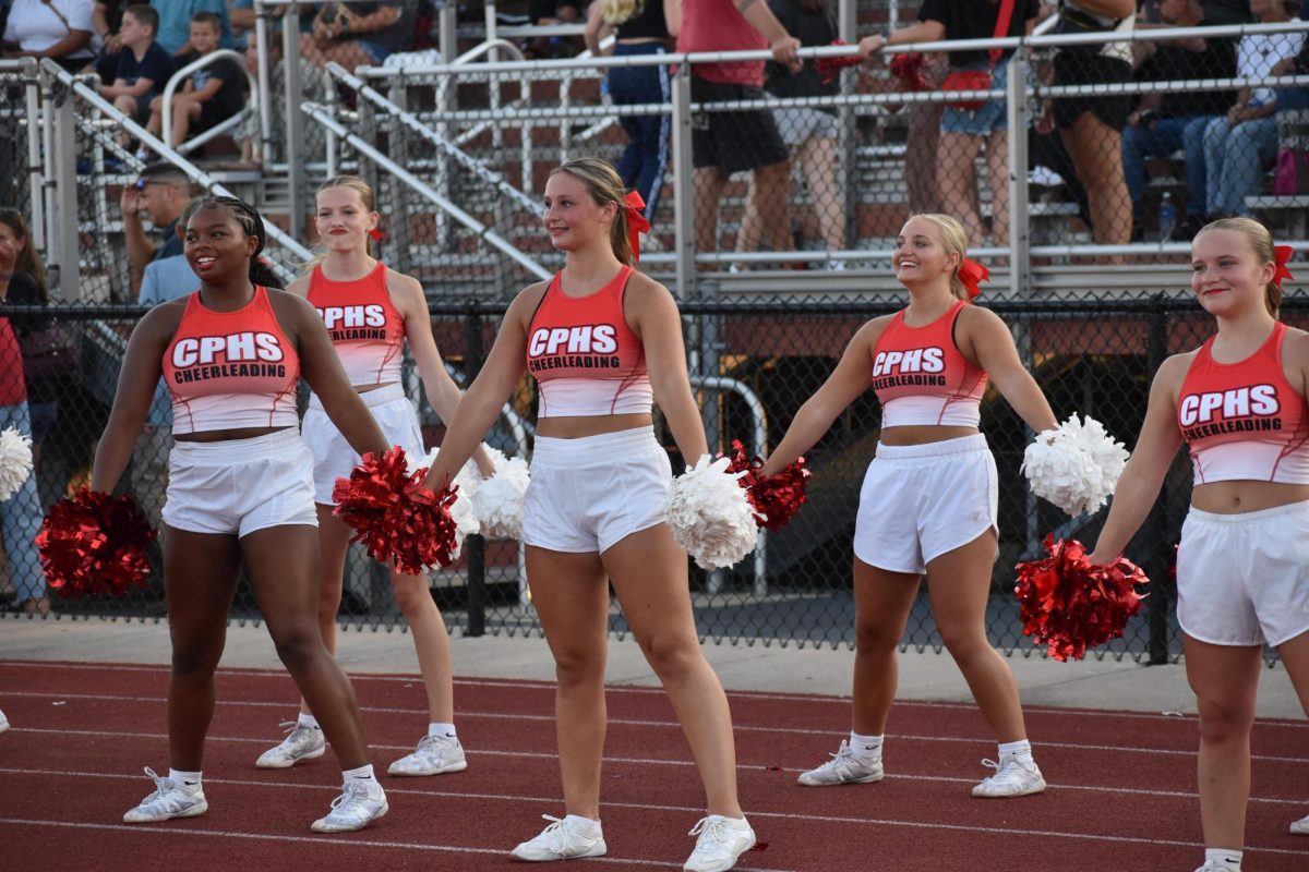 The cheer team cheer on the football players.