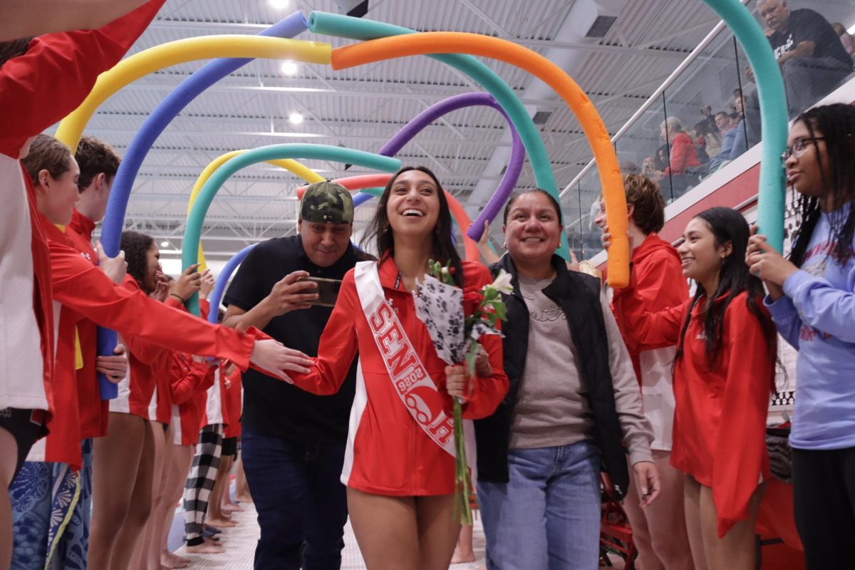 Senior Alex Calzonzi and her family walk through the tunnel made by teammates.