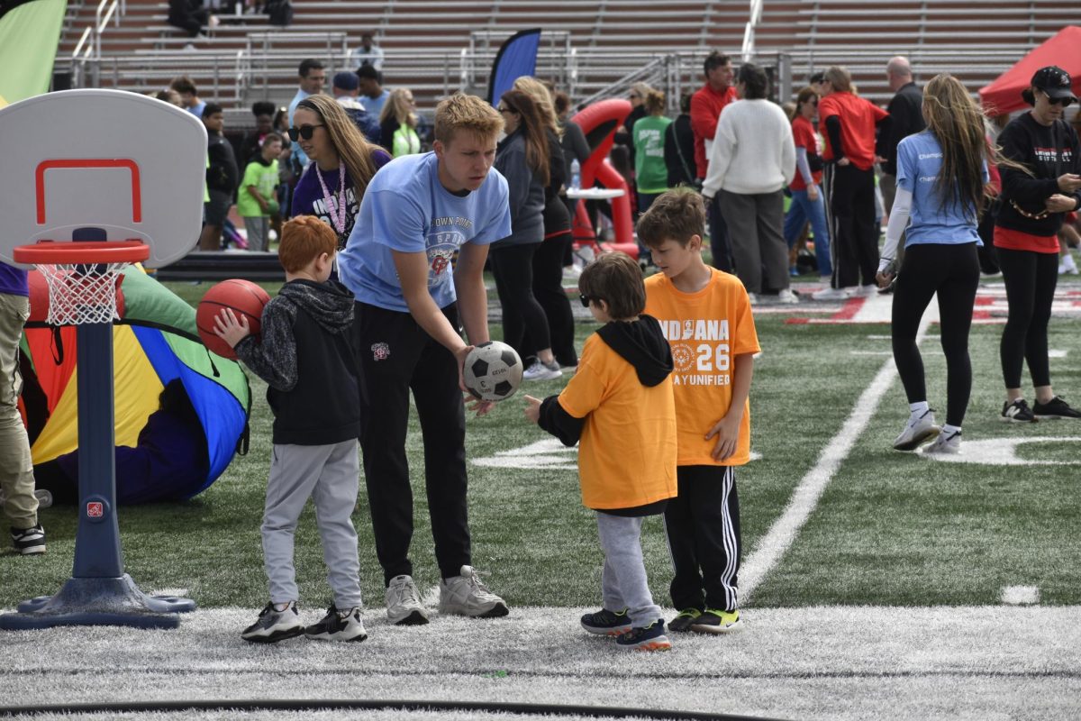 Bruce Boomsma (10) hands off a ball to student participants during field day.
